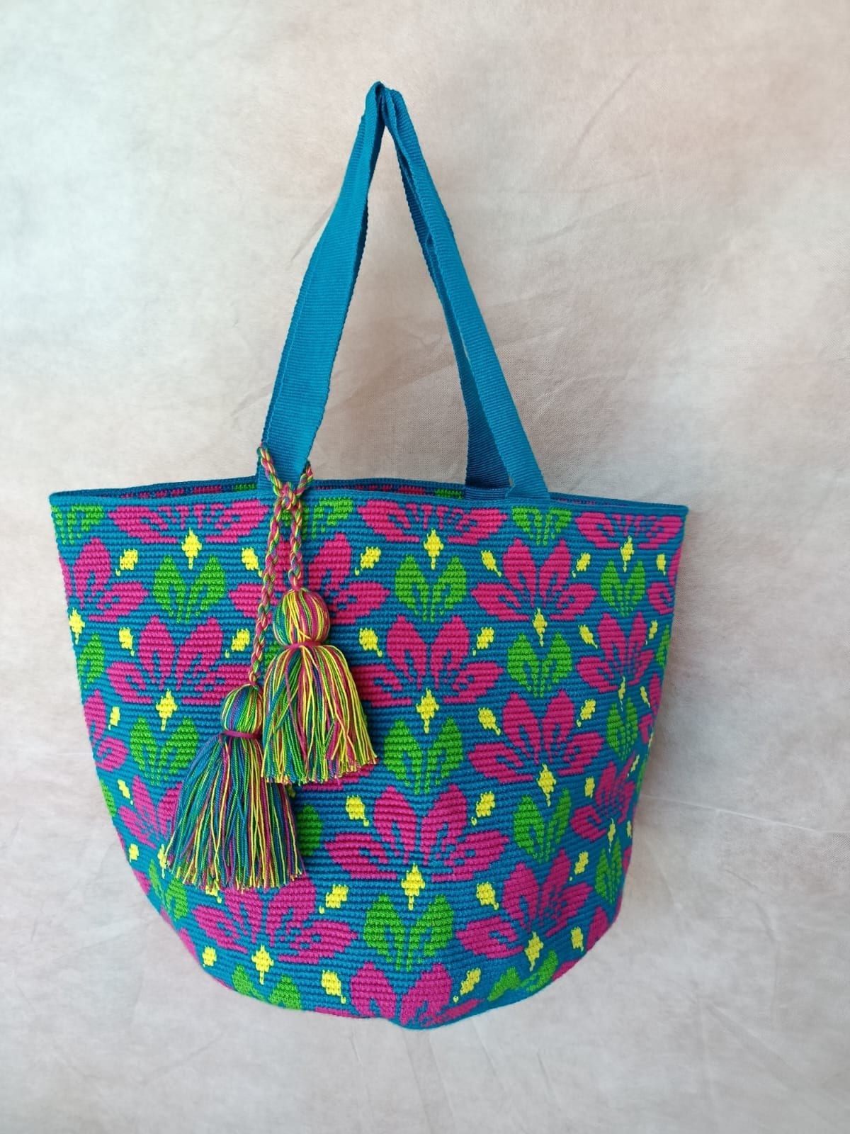 Totem Fucsia, hand-crocheted bag. Fuchsia flowers and green leaves on turquoise, with yellow dots.