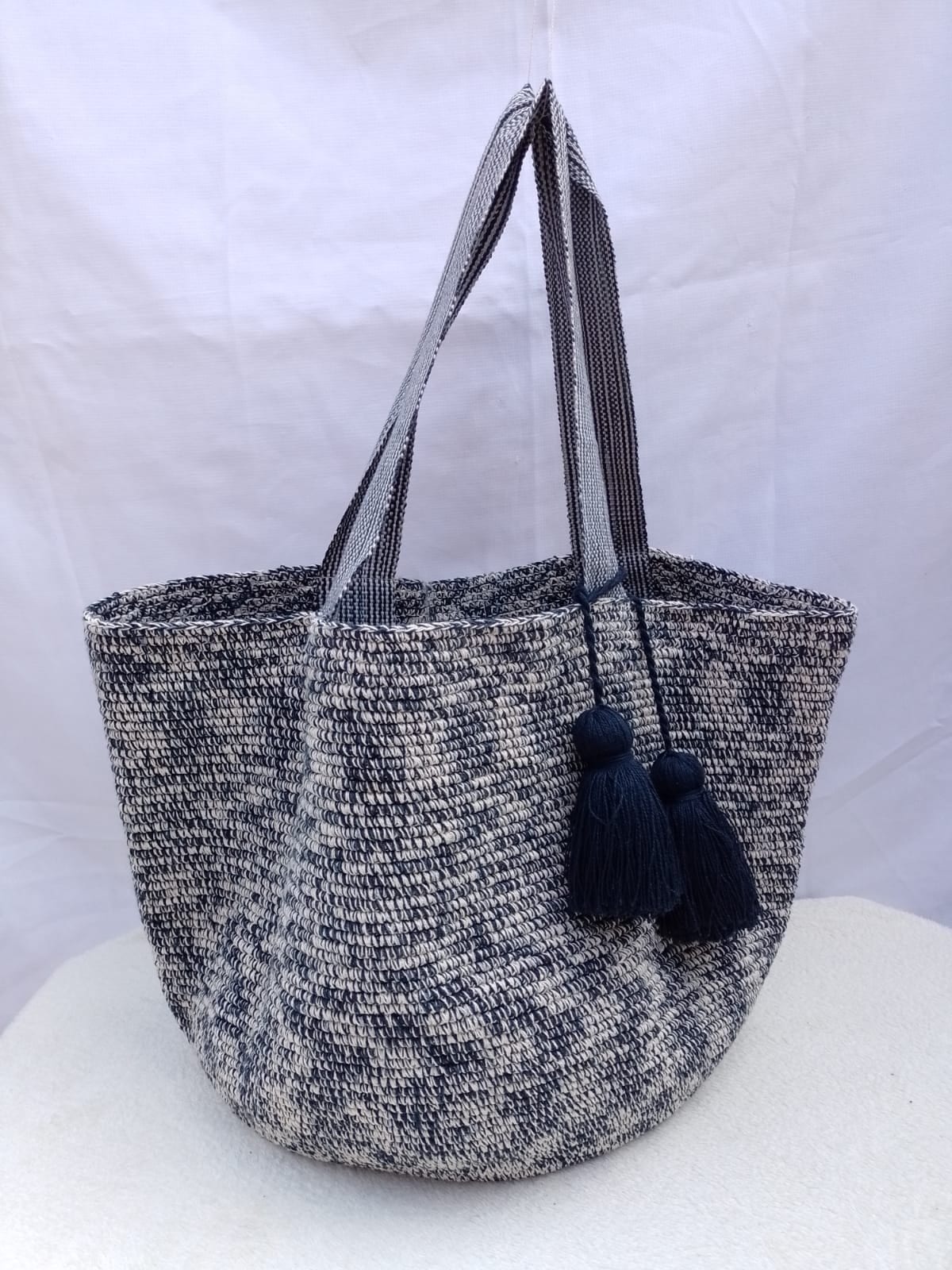 Totem Noche, bolso tejido a mano en crochet. Azul noche y marfil jaspeado, asas a rayas finas y dos borlas azul noche.