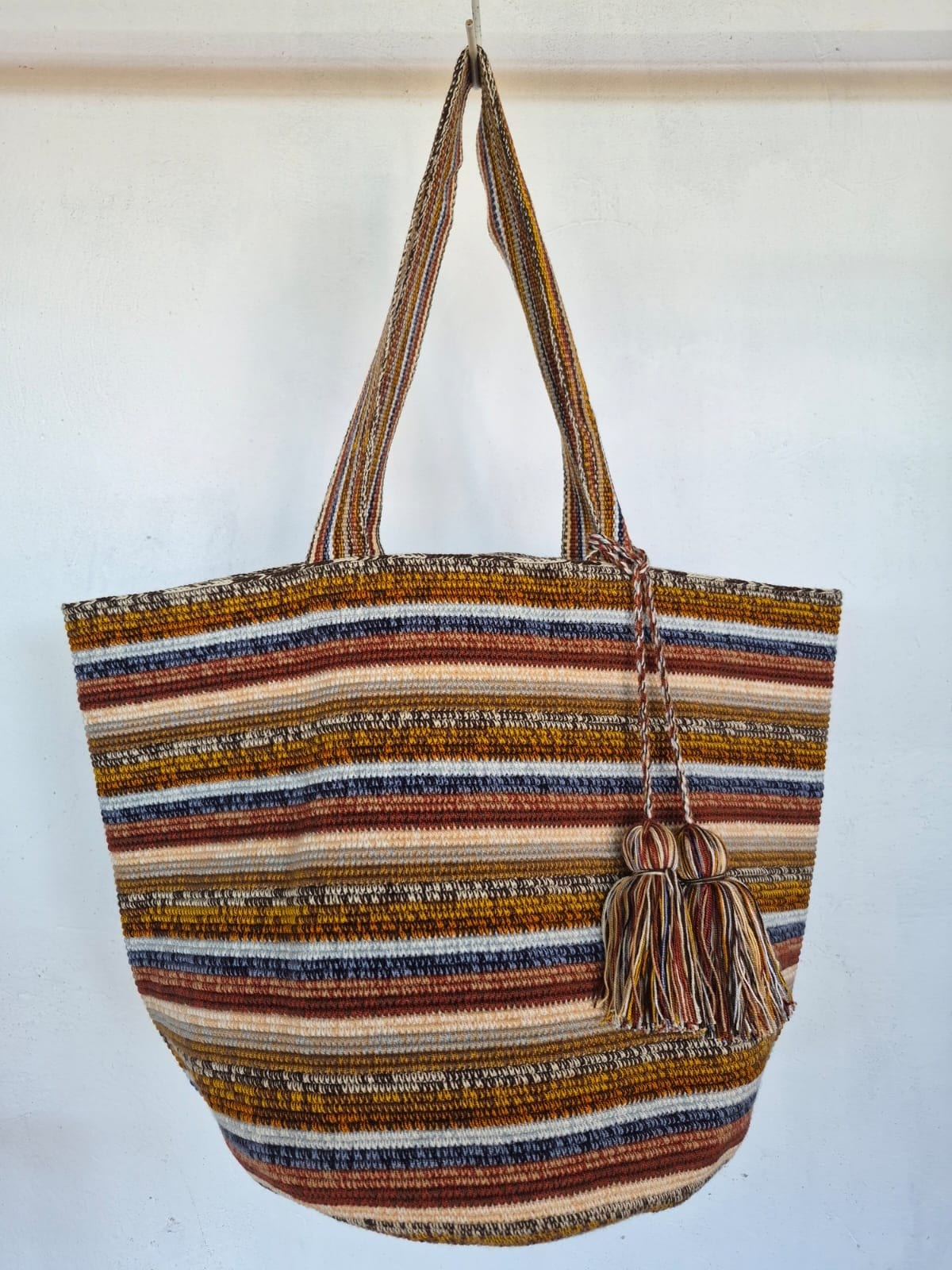 Totem Tarde, hand-crocheted bag. Bands of ochre, terracotta, slate blue and peach, with two matching tassels.